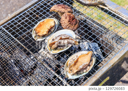 バーベキュー網の上で焼かれる食材 129726083