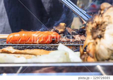 バーベキュー網の上で焼かれる食材 129726085