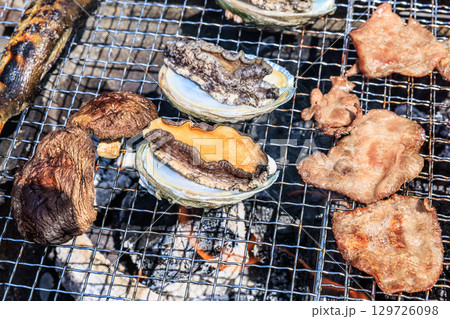 バーベキュー網の上で焼かれる食材 129726098