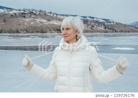 portrait woman middle aged enjoying winter in nature frozen lake surrounded by mountains. closeup. 129726176