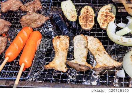 バーベキュー網の上で焼かれる食材 129726190