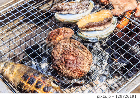 バーベキュー網の上で焼かれる食材 バーベキュー網の上で焼かれる食材 129726191