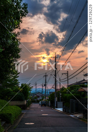 雲間から覗く夕日に照らされる街並み 空と街を黄金色に染めていく夕日 雲間から覗く夕日に照らされる街並み 空と街を黄金色に染めていく夕日 129726229