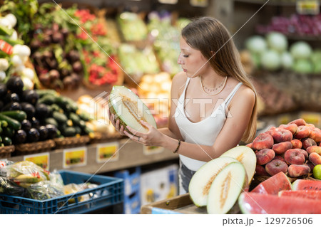Young woman choosing a melon in a fruit store 129726506