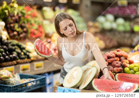 Woman near vegetable stand in store choose watermelon Woman near vegetable stand in store choose watermelon 129726507