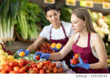 Women sellers lay out vegetables and fruits Women sellers lay out vegetables and fruits 129726510