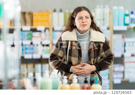 Woman experiences abdominal pain while buying in supermarket Woman experiences abdominal pain while buying in supermarket 129726563