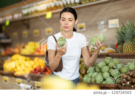 Adult woman choosing artichoke in vegetable shop Adult woman choosing artichoke in vegetable shop 129726565