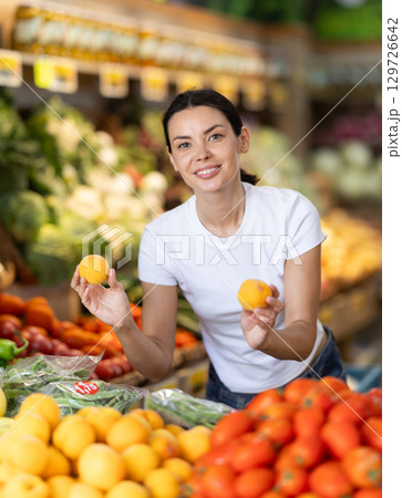 Young woman choosing ripe tasty peaches in grocery department of supermarket 129726642