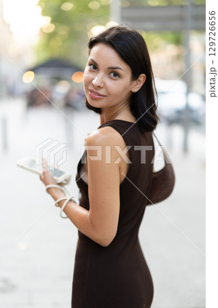 Slender female brunette with phone walks in vicinity of Passeig Nou in Barceloneta 129726656