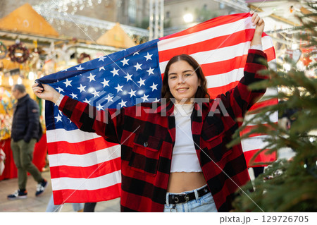 Happy girl with flag of United States at city Christmas market 129726705