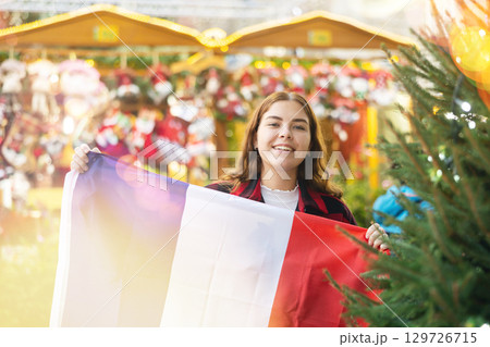 Smiling girl with flag of France walking on street Christmas fair Smiling girl with flag of France walking on street Christmas fair 129726715