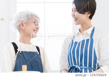 キッチンに立つ若い女性とシニア女性　料理イメージ 129726829
