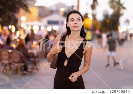 Smiling girl walks around old city district Barceloneta, pedestrian promenade embankment. 129726849