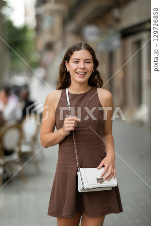 Nice european young girl wearing short dress posing on street near cafe areas 129726858