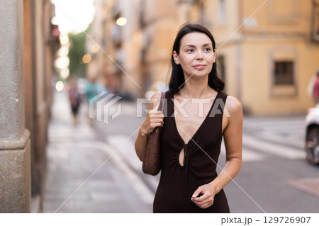 Woman walks along narrow street between buildings of 19th century 129726907