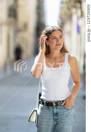 Young smiling girl walks along city street 129726909