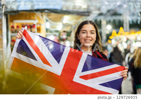Cheerful girl with British flag at Christmas street fair Cheerful girl with British flag at Christmas street fair 129726935