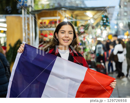 Happy girl with French flag in street Christmas fair Happy girl with French flag in street Christmas fair 129726938