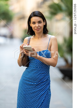 Young woman with mobile phone on city street Young woman with mobile phone on city street 129726986