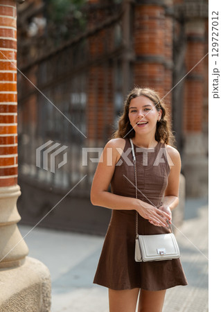 Young female tourist dressing in dress enjoying walk near columns of architectural complex of Hospital de la Santa Creu i Sant Pau in Barcelona 129727012