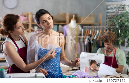 Female dressmaker applying textile on woman 129727131