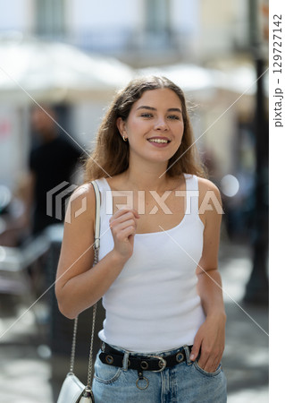 Young smiling girl walks along city street 129727142