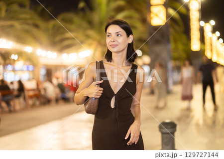 Woman walking along coastal promenade at night in Barcelona 129727144