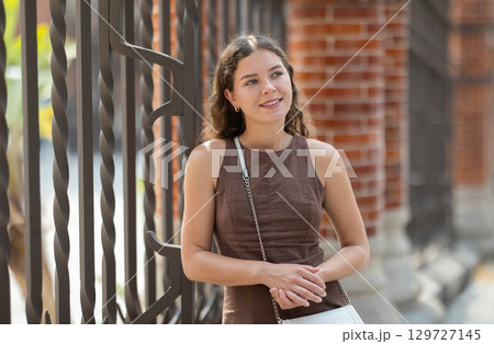 Young woman standing near the metal fence Young woman standing near the metal fence 129727145