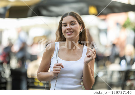 Cheerful girl walking at the street among architecture with bag Cheerful girl walking at the street among architecture with bag 129727146