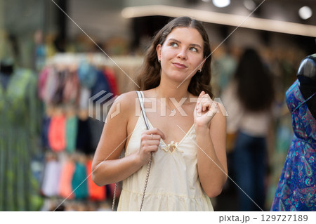 Young girl in white dress is looking for something at street market - looking at goods with interest 129727189