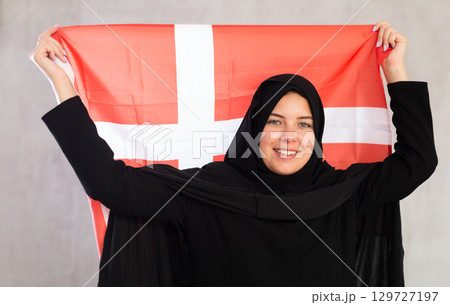 Happy young woman dressed in traditional islamic clothes with danish flag 129727197