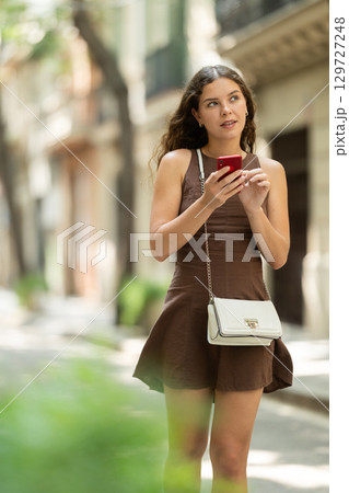 Young tourist woman looking map or searching address with smartphone walking streets of Barcelona Young tourist woman looking map or searching address with smartphone walking streets of Barcelona 129727248