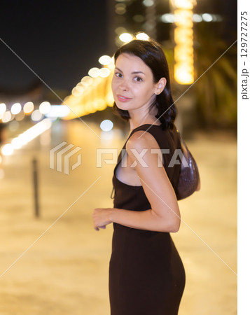 At night, smiling girl walks around old city district Barceloneta, in vicinage of Citadel Park 129727275