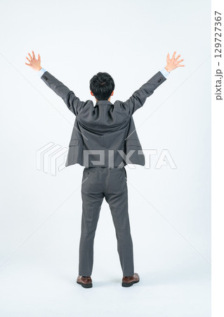 バンザイする男性ビジネスパーソンの後ろ姿の全身写真 129727367