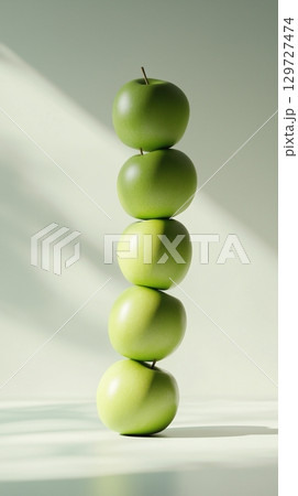 A stack of green apple slice fruit balancing on top with solid background 129727474
