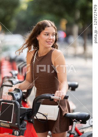 young woman stands in front of a cart of bicycles in the city 129727479
