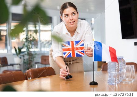 Businesswoman arranging the flags of Great Britanian and France for presentation and negotiations Businesswoman arranging the flags of Great Britanian and France for presentation and negotiations 129727531