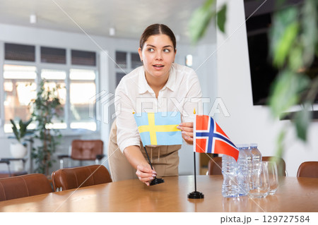 female assistant prepares conference room for diplomats of Norwау and Sweden 129727584