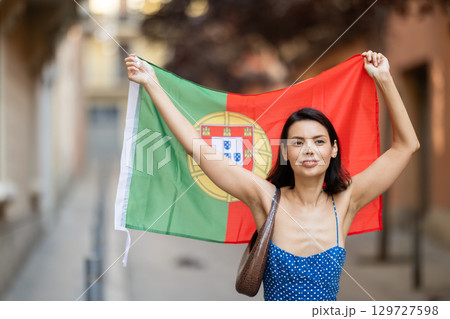 Girl waving Portugal flag on street of summer city Girl waving Portugal flag on street of summer city 129727598