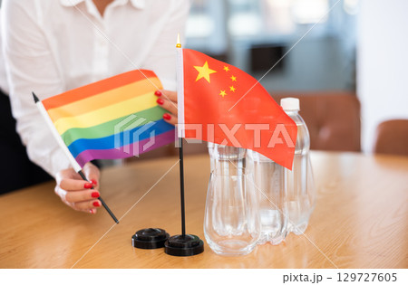 Unrecognizable girl sets midget flags of Chinа and LGBT before international negotiations Unrecognizable girl sets midget flags of Chinа and LGBT before international negotiations 129727605