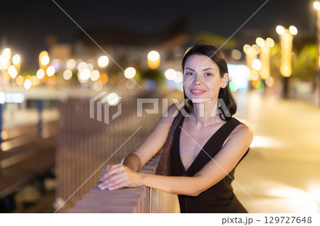 At night, smiling girl walks around old city district Barceloneta, in vicinage of Citadel Park 129727648