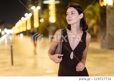 Woman walking along coastal promenade at night in Barcelona 129727718