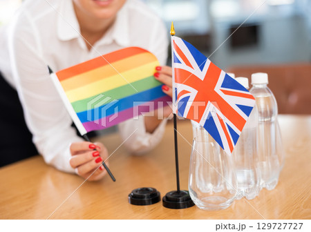 Little flag of Great Britain on table and LGBT flag put next to it by young woman 129727727