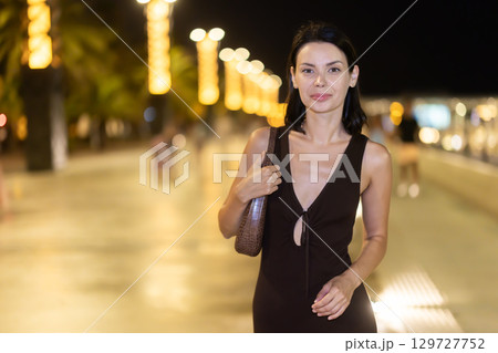 At night, smiling girl walks around old city district Barceloneta, in vicinage of Citadel Park 129727752