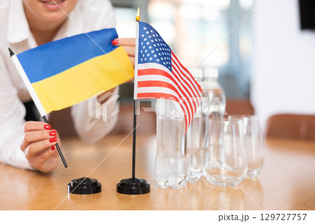 Flags of Ukraine and USA stand on negotiating table in office Flags of Ukraine and USA stand on negotiating table in office 129727757