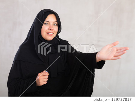 Young female in black hijab pointing at you - Portrait of young woman pointing her finger Young female in black hijab pointing at you - Portrait of young woman pointing her finger 129727817