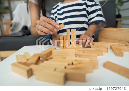 Creative Play. Mother helping child build with wooden blocks at home. 129727948