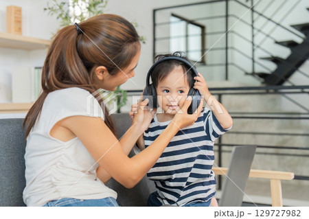 Joyful Moments. Mother helping child wear headphones for gaming. Joyful Moments. Mother helping child wear headphones for gaming. 129727982
