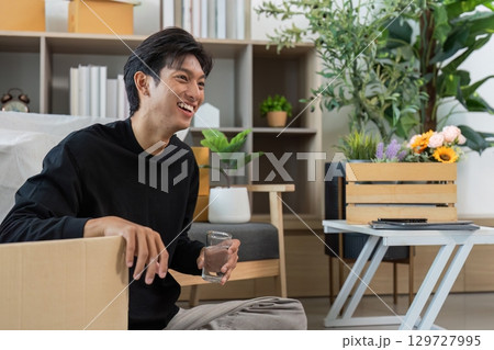 Young man enjoying a moment of relaxation at home with a glass of water 129727995